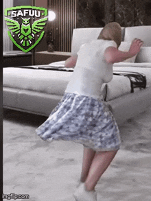 a woman in a skirt is dancing in front of a bed in a bedroom .