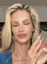 a woman in a blue shirt has a tattoo on her finger
