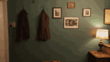 a room with pictures on the wall and a lamp on a nightstand