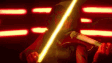 a person is playing a violin in a dark room with a light saber in their hand .