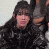 a woman in a black jacket is making a funny face while sitting in front of a group of women .