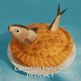 a pie with a fish on top of it and the words common english delicacy below it