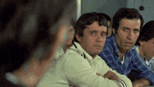 a group of men are sitting at a table with their arms crossed and looking at something