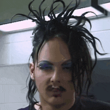 a close up of a person 's face with a mustache and purple eye shadow