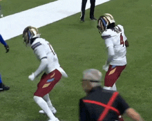 two football players are dancing on the field and one has the number 4 on his shirt
