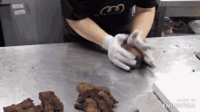 a person wearing gloves holds a piece of chocolate on a table with the words made in animatica on the bottom