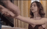 a woman in a red dress is holding a man 's hand while standing on a bed .