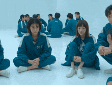 a group of people are sitting on the floor and one has the number 067 on her back