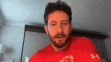 a man with a beard is wearing a red under armour t-shirt