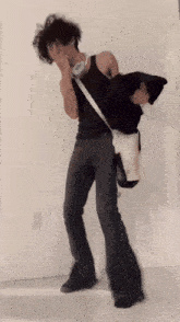 a man in a black tank top is holding a black cat on his shoulder
