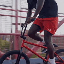a man wearing red shorts with the number 40 on them rides a red bike