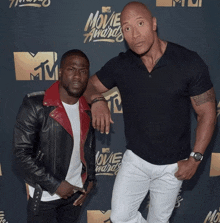 two men standing next to each other in front of a movie awards sign