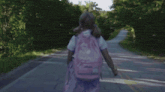 a girl with a backpack is walking down the road