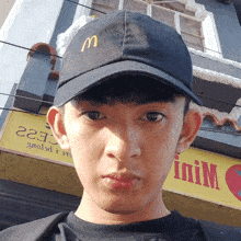a young man wearing a mcdonald 's hat stands in front of a yellow sign
