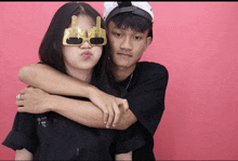 a girl wearing a pair of middle finger glasses is hugging a boy