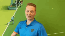 a man wearing a blue adidas shirt gives a thumbs up sign