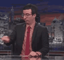 a man in a suit and red tie is standing in front of a city skyline .