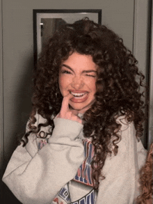a woman with curly hair wearing a sweatshirt that says ' nba ' on it