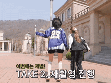 two girls walking in front of a building with the words take 2 on the bottom right