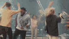 a group of people are dancing on a stage with a woman singing into a microphone