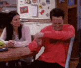 a man in a red sweater is sitting at a table with a woman