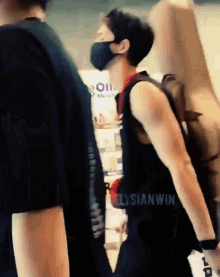 a man wearing a mask and carrying a guitar case has the word elysianwin on his back