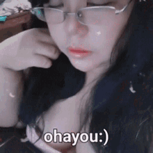 a woman wearing glasses and a pink top says ohayou )
