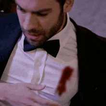 a man in a tuxedo and bow tie has blood on his chest