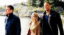 three people are standing next to each other on a beach .