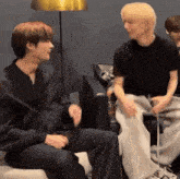 a group of young men are sitting on a couch and talking to each other