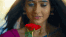 a close up of a woman smelling a red rose .