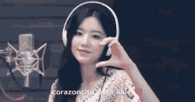 a woman wearing headphones is making a heart shape with her hands .