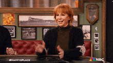 a woman sitting at a table with a nbc logo on the bottom