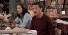 a man and a woman are sitting at a table with wine glasses on it