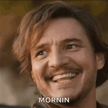 a man with a beard and mustache is smiling with the word mornin on his face .