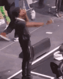 a man is standing on a stage with his arms outstretched in front of a crowd