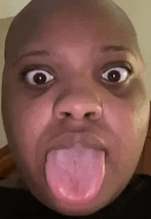 a bald man is sticking his tongue out .