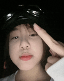 a young girl wearing a hat and goggles is making a peace sign with her finger