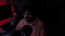 a man wearing headphones is sitting in front of a microphone in a dark room ..