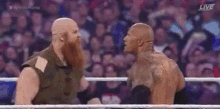 two men with beards are standing in a wrestling ring and talking to each other .