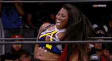 a woman is laughing in a wrestling ring while sitting in the audience .