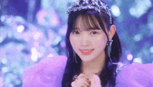 the girl is wearing a purple dress and a tiara and smiling .