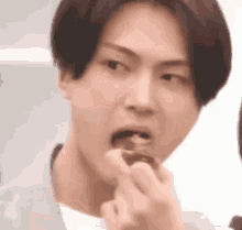 a close up of a young man eating a piece of chocolate .
