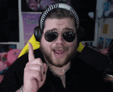 a man wearing sunglasses and headphones points his finger up