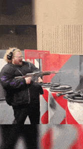 a man wearing headphones and glasses is holding a gun in a shooting range