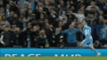 a soccer player celebrates a goal in front of a crowd with a sign that says peace