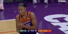 a female basketball player wearing a number 75 jersey is standing on a purple court .