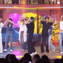 a group of people are dancing on a stage and one of them is wearing a hat