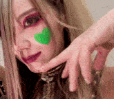 a woman with green paint on her face is making a funny face
