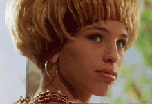 a close up of a woman 's face wearing hoop earrings and a headband